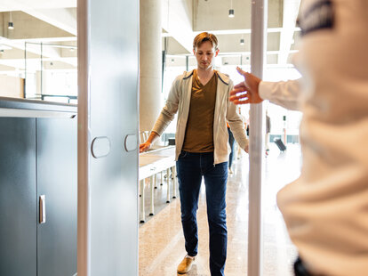 Focused shot of a young adult male tourist walking through a metal scanning machine at airport security before going on vacation.