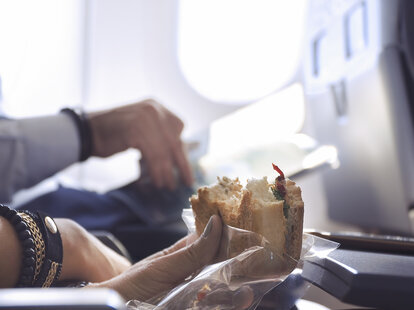 passenger eating a sandwich on a plane