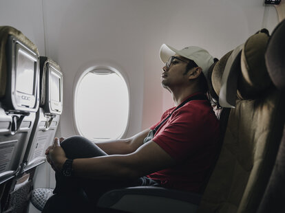 Man sitting in airplane seat, looking slightly cramped.