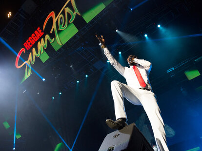 a man in a white suit on stage, seen from below