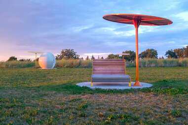 a park with futuristic dome art and a chair and umbrella