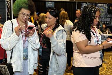 Three people who are attending Crime Con, standing at Madison McGhee&rsquo;s booth.