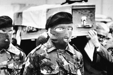Masked members of an IRA honor guard bear the coffin of hunger striker Bobby Sands to his grave