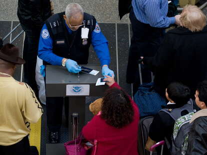 A Transportation Security Administration (TSA) official (2nd R) checks the identification of passengers prior to entering a security checkpoint at Ronald Reagan Washington National Airport in Arlington, Virginia, just outside Washington, DC, on December 2