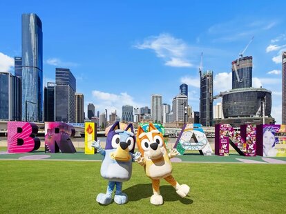 Bluey and Bingo characters standing in front of the Brisbane city sign in Australia.