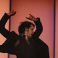 a sweaty man dancing flamenco, with his arms thrown up in the air 