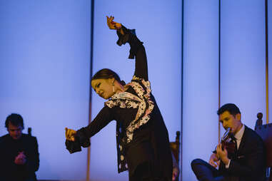 a woman in black dancing flamenco in a dramatic pose