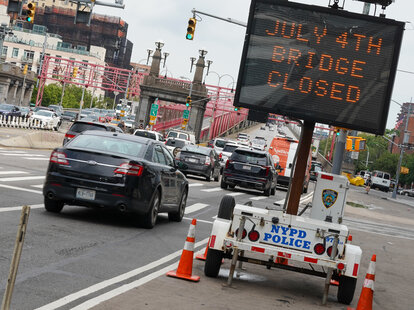 A sign notifies travelers that the bridge will close on July 4th at the Williamsburg Bridge in New York