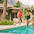 A small group of women jumping into a villa swimming pool. 