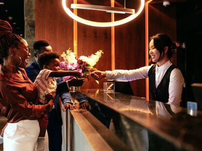 Happy child takes hotel room key at reception