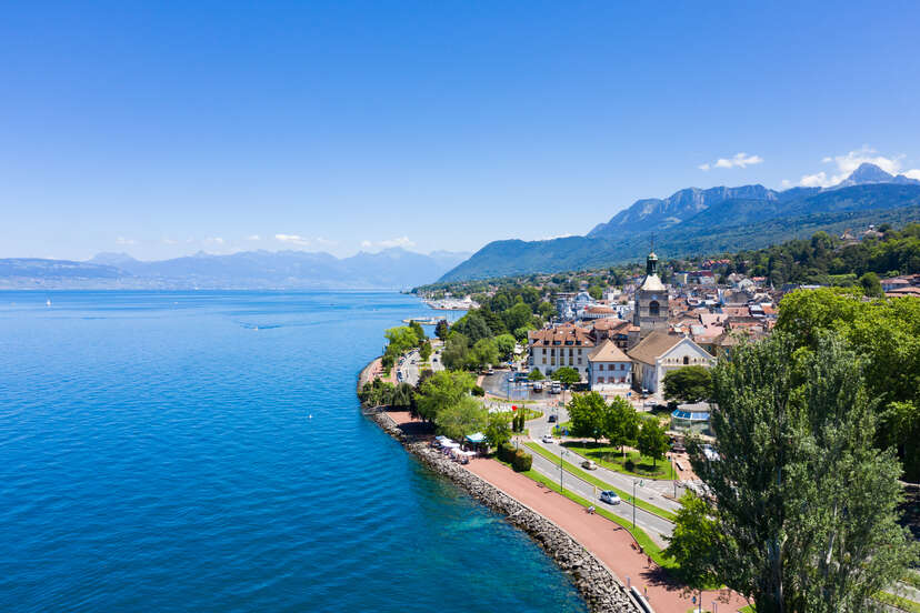 a beautiful town on a lake, with mountains in the background 