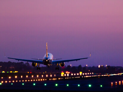 Airplane landing on the Barcelona airport at night with nice detail view of the illuminated track.
