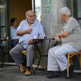 Greek men drink coffee in a street cafe in Athens, Greece.