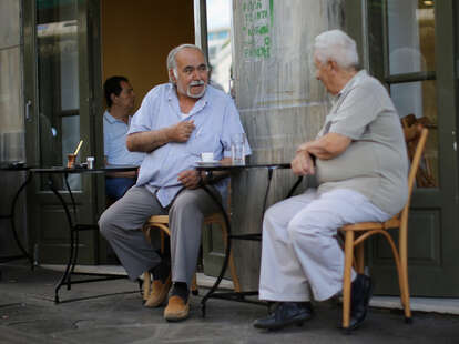 Greek men drink coffee in a street cafe in Athens, Greece.