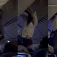 A man being helped down from the overhead compartment after being thrown by turbulence. 