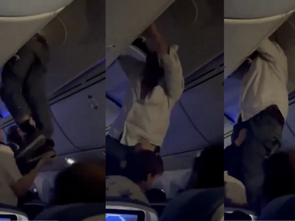 A man being helped down from the overhead compartment after being thrown by turbulence.