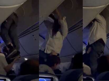 A man being helped down from the overhead compartment after being thrown by turbulence. 