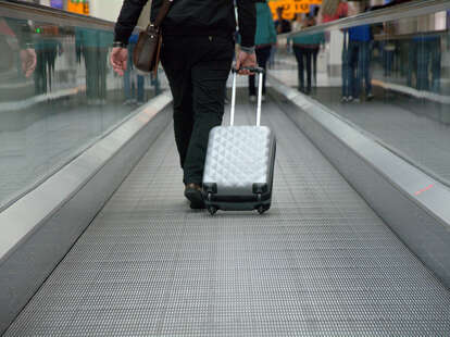 Traveling on a moving walkway at the airport with a suitcase