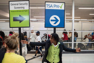 An aiport employee helps travelers navigate long lines for security screening at the Atlanta airport