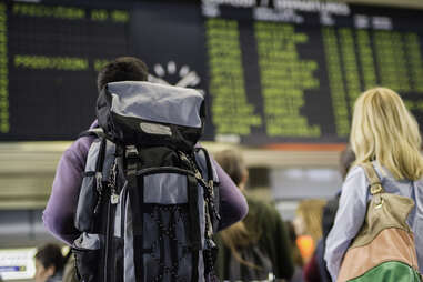 Group of people standing in front of an airport arrival departure board