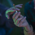 A close-up shot of two people passing a joint of marijuana