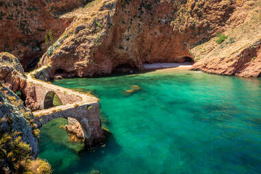 blue green waters surround ruins and a gave at a nature reserve in Portugal