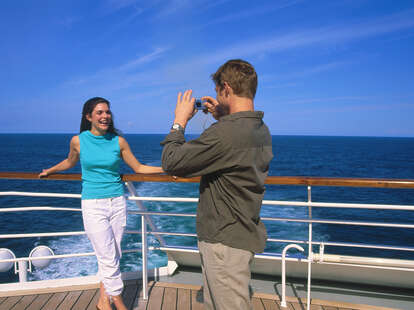 A couple taking picture on the deck of cruise ship at sea.