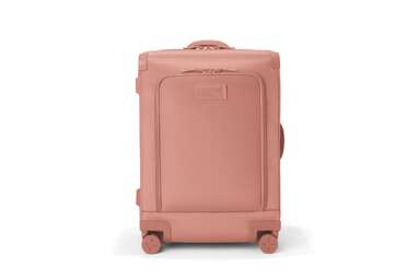 A coral colored soft-sided suitcase from Dagne Dover. 