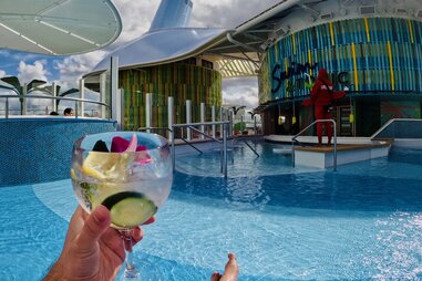 A photo of a hand holding a cocktail on the pool deck.