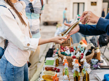 Young female tourist looking at the homemade liquors sold by the street vendors on the street in Dubrovnik in Croatia.