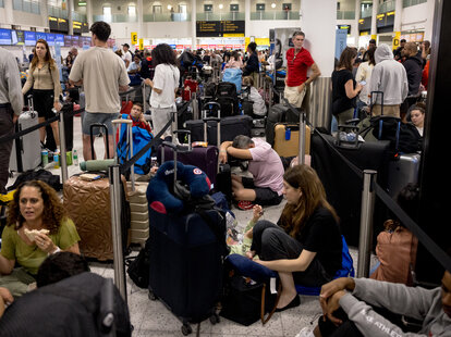 Passengers queue at Gatwick Airport amid a global IT outage on July 19, 2024 in Crawley, United Kingdom. Businesses, travel companies and Microsoft users across the globe were among those affected by a tech outage today.