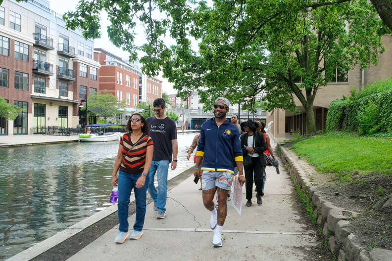 a group of people walking along a river. one man has a headset. 