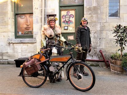 a man and a woman cosplaying as steampunk characters with a motorbike on the streets of oamaru new zealand