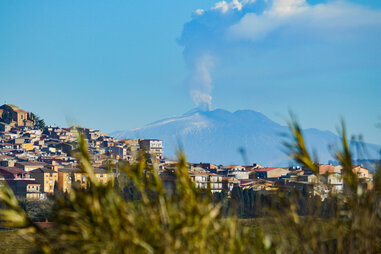 an Italian village with a smoking volcano in the background