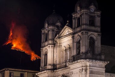 a volcano erupting with a church in the foreground
