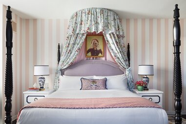 A hotel room with a portrait of Dolly Parton hanging above the bed.