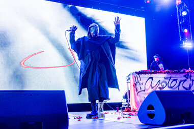 Yasiin Bey performs and two people relax by the pond.