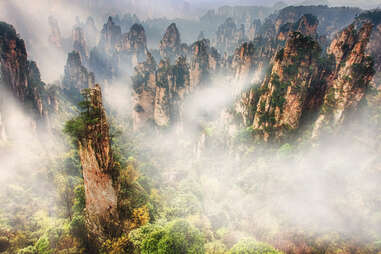 The Rock formations in Tianzishan area in Zhangjiajie National Park, Hunan province, China. Sunlight hitting the morning fogs in the valley.