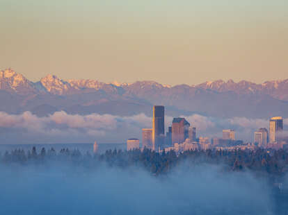Seattle skyline and Olympic mountains viewed from Bellevue at sunrise on a foggy morning.