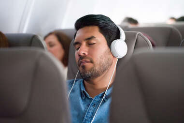 a man sleeping with his headphones, a carry-on essential
