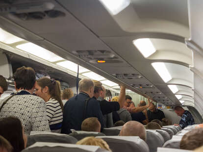 Landing aircraft, people stand in the aisle between the seats and take out the luggage.