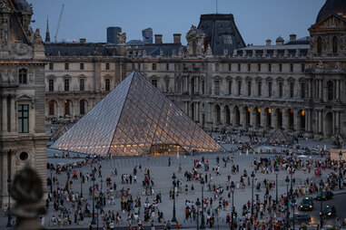 Tourists stand next to the Louvre Pyramide designed by Chinese-US architect Ieoh Ming Pei, during the Paris 2024 Olympic and Paralympic Games in Paris.
