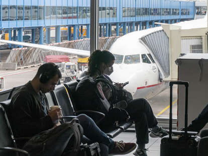 Passenger wearing a face mask as seen waiting in front of an Airbus A320 aircraft at the gates area.