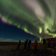 group of people watching northern lights in iceland