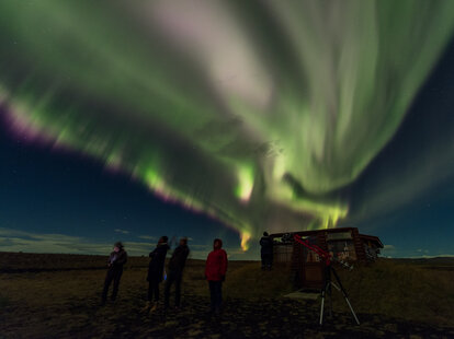 group of people watching northern lights in iceland