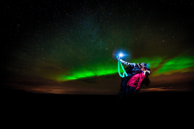 couple taking a selfie while kissing under the northern lights
