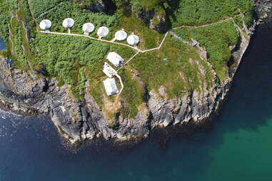 white tents on a rocky island in the ocean 