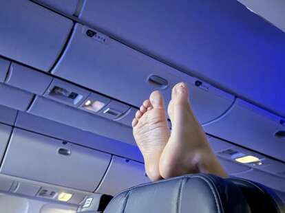 A picture of bare feet on the top of a plane seat.