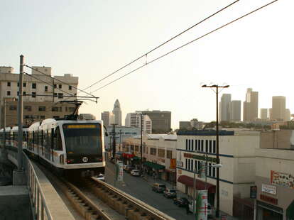 los angeles metro train rolls into a station with downtown la in the background