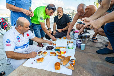 men eating a communal breakfast outside